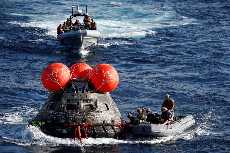 U.S. Navy divers attach winch cables to NASA's Orion capsule after being successfully secured by a NASA and U.S. Navy team, off the coast of Baja California, Mexico, 11 December 2022. The Orion capsule returns back to earth after a 25.5-day mission obiting the moon and back to Earth in a recovery operation involving the US Navy and NASA. CAROLINE BREHMAN/Pool via REUTERS